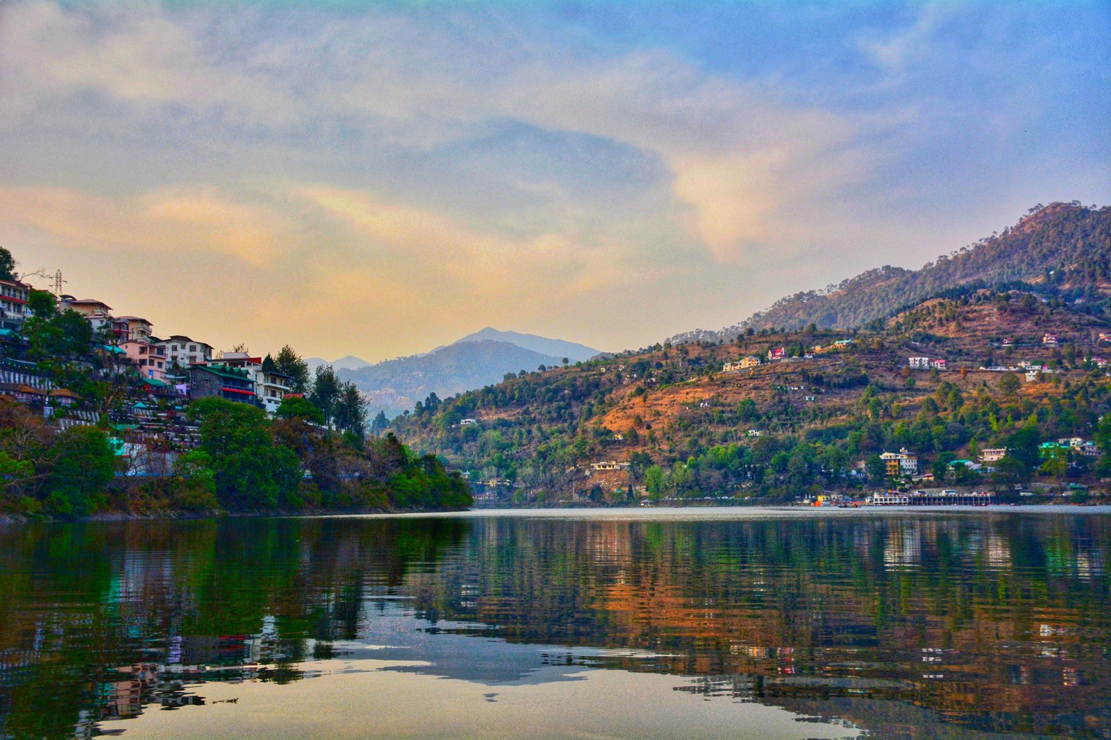 Tranquil Bhimtal lake with traditional wooden boats at sunrise